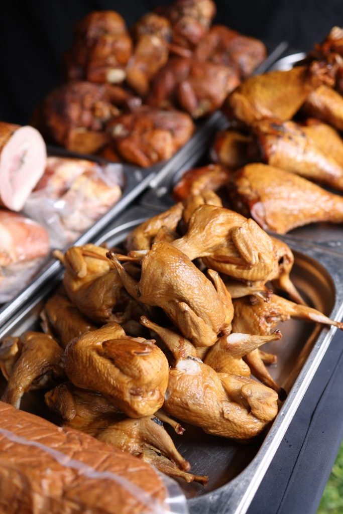 Delicious variety of smoked meats arranged on a tray at a market stall.